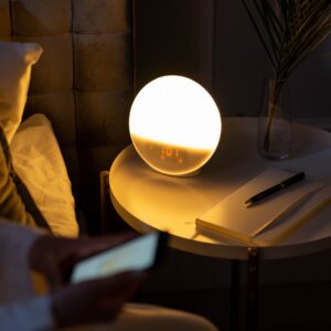 Warm bedside setting with a smart alarm clock and a cozy ambiance.