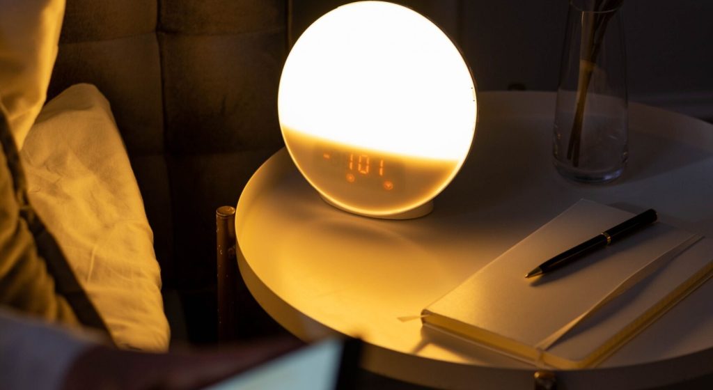 Warm bedside setting with a smart alarm clock and a cozy ambiance.